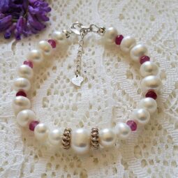 Elegant bracelet featuring 8 mm freshwater pearls and 3 mm pink rubies, accented with sterling silver spacers and an adjustable clasp.