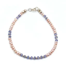 Delicate bracelet featuring 3 mm genuine tanzanite gemstones and peach freshwater pearls, accented with sterling silver spacers and clasp.