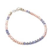 Delicate bracelet featuring 3 mm genuine tanzanite gemstones and peach freshwater pearls, accented with sterling silver spacers and clasp.