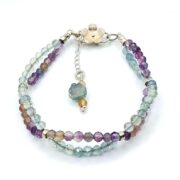 A stunning double-strand fluorite bracelet with a unique helix design, featuring faceted fluorite beads and a sterling silver clasp with a floral detail.