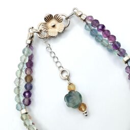 A stunning double-strand fluorite bracelet with a unique helix design, featuring faceted fluorite beads and a sterling silver clasp with a floral detail.