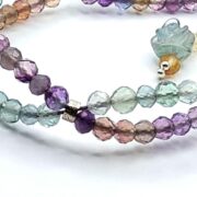 A stunning double-strand fluorite bracelet with a unique helix design, featuring faceted fluorite beads and a sterling silver clasp with a floral detail.