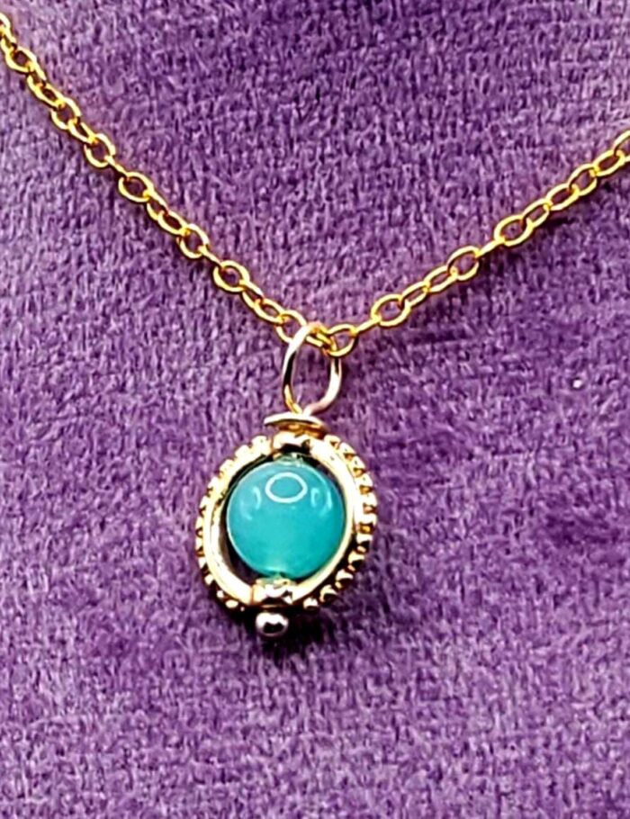 Dainty 6mm Blue Amazonite Pendant in Gold Frame against purple background